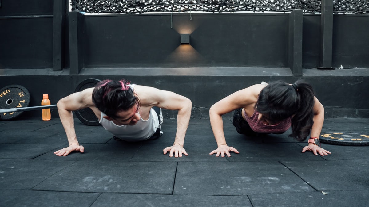 Two adults doing push-ups in an indoor gym setting in Mexico City, promoting a fit and healthy lifestyle.